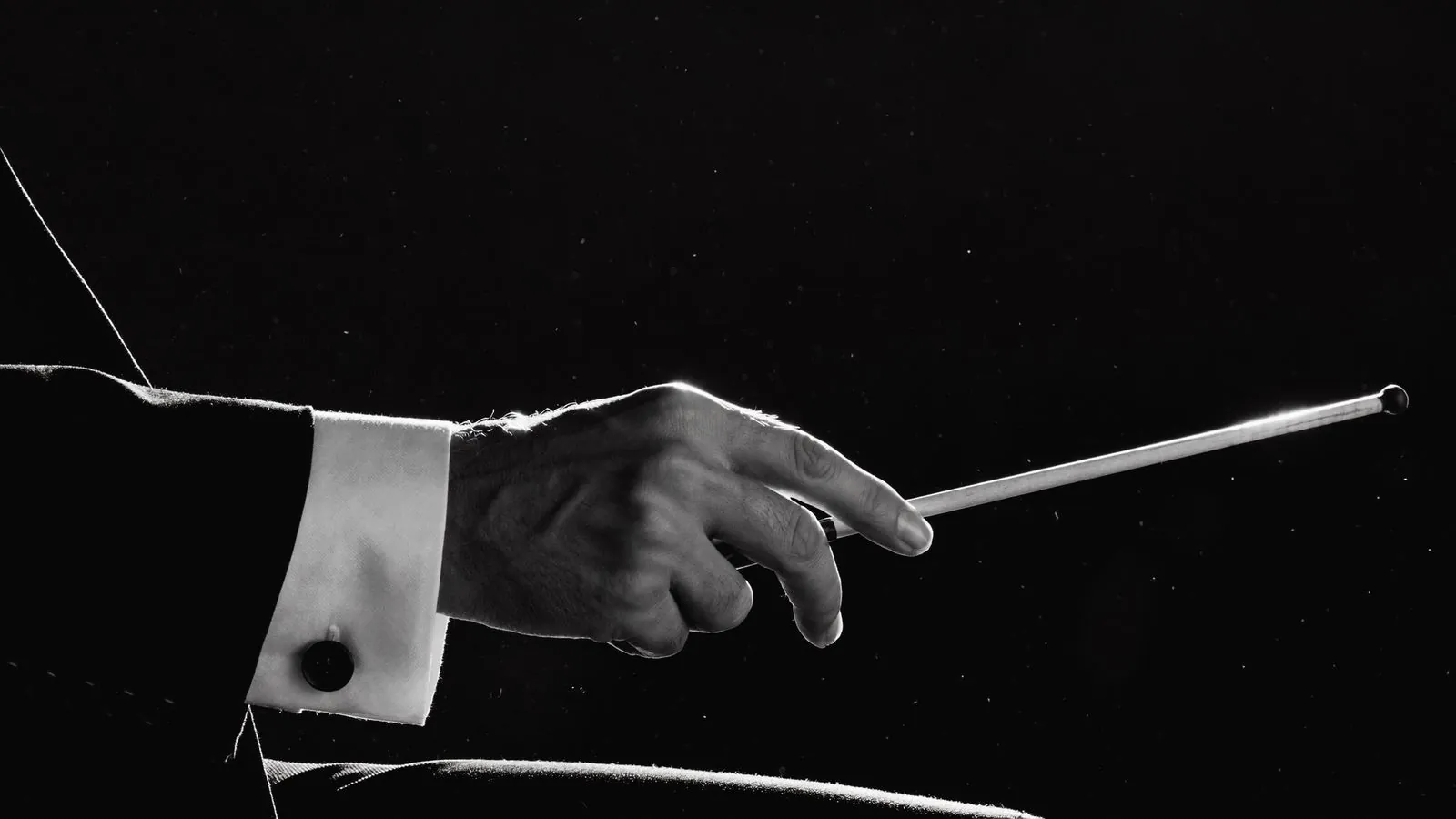 Mão de maestro segurando batuta em preto e branco de alto contraste